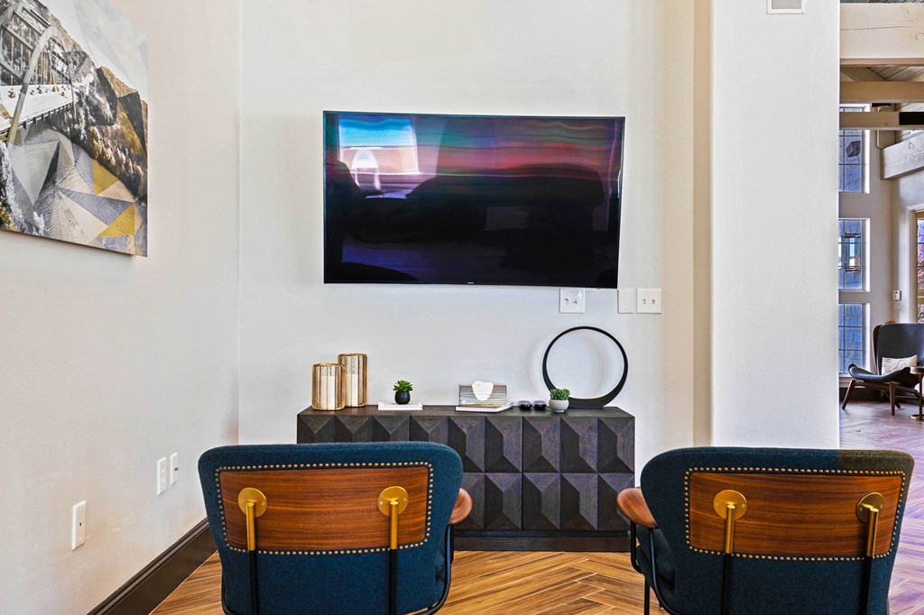 a living room with two blue chairs and a painting on the wall at The Olivine, Austin, TX